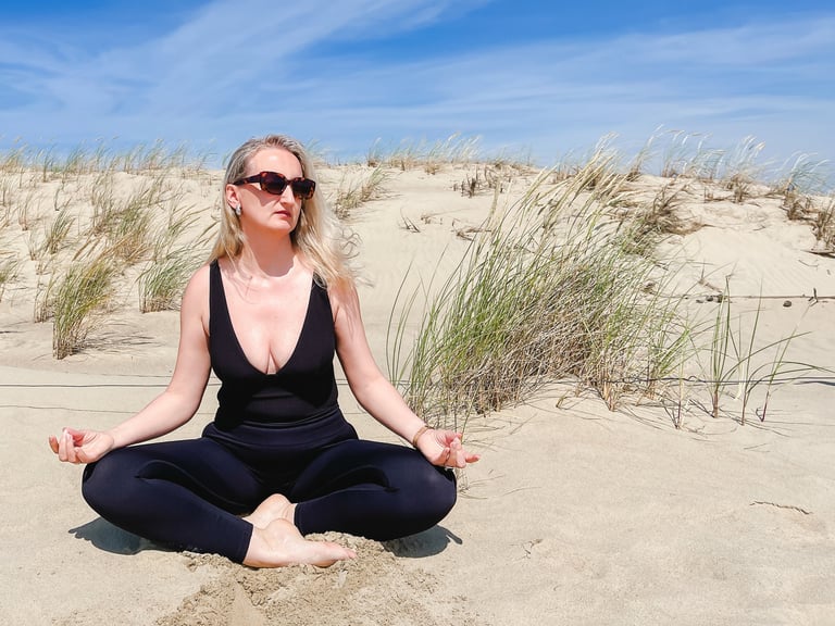 Middle aged woman doing yoga on the Dead Dunes, or Grey Dunes in Curonian Spit, Neringa during solo travel to Lithuania, embracing a calm and natural lifestyle