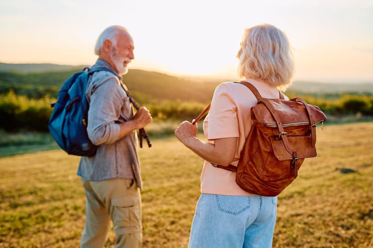 Active senior couple with backpacks enjoying a sunset hike outdoors, embracing health and well-being in retirement