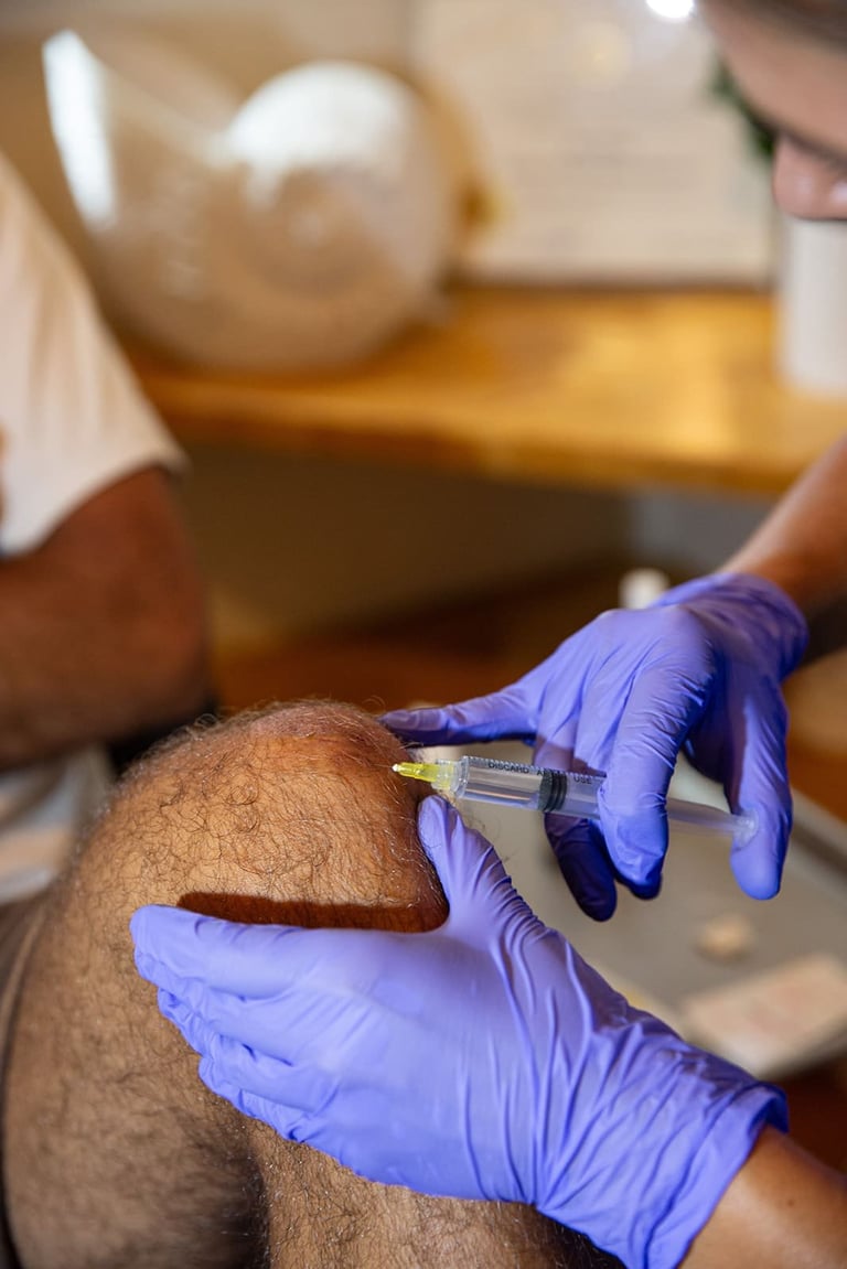 Healthcare worker in purple gloves administering an injection into a patients arm with a medical syringe