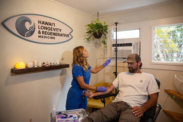 Healthcare practitioner in blue scrubs examining a seated male patient in a wellness clinic with Hawaii Longevity and Regenerative Medicine signage